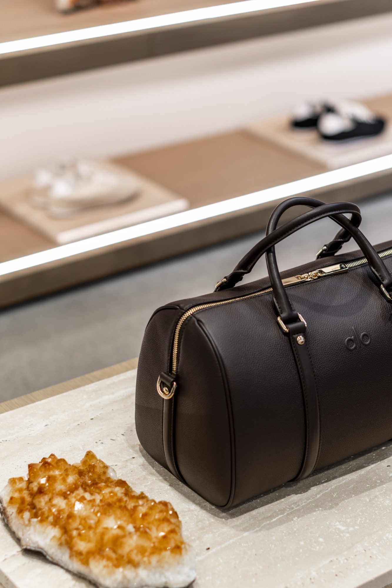 Detail of a leather holdall on a stone plinth beside a citrine crystal