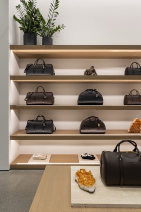 Oak wall shelving with leather bags, styled with a citrine crystal on a stone plinth