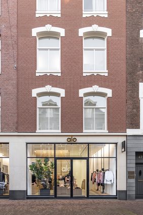 Brick shopfront with an illuminated brand sign above full-height glazing