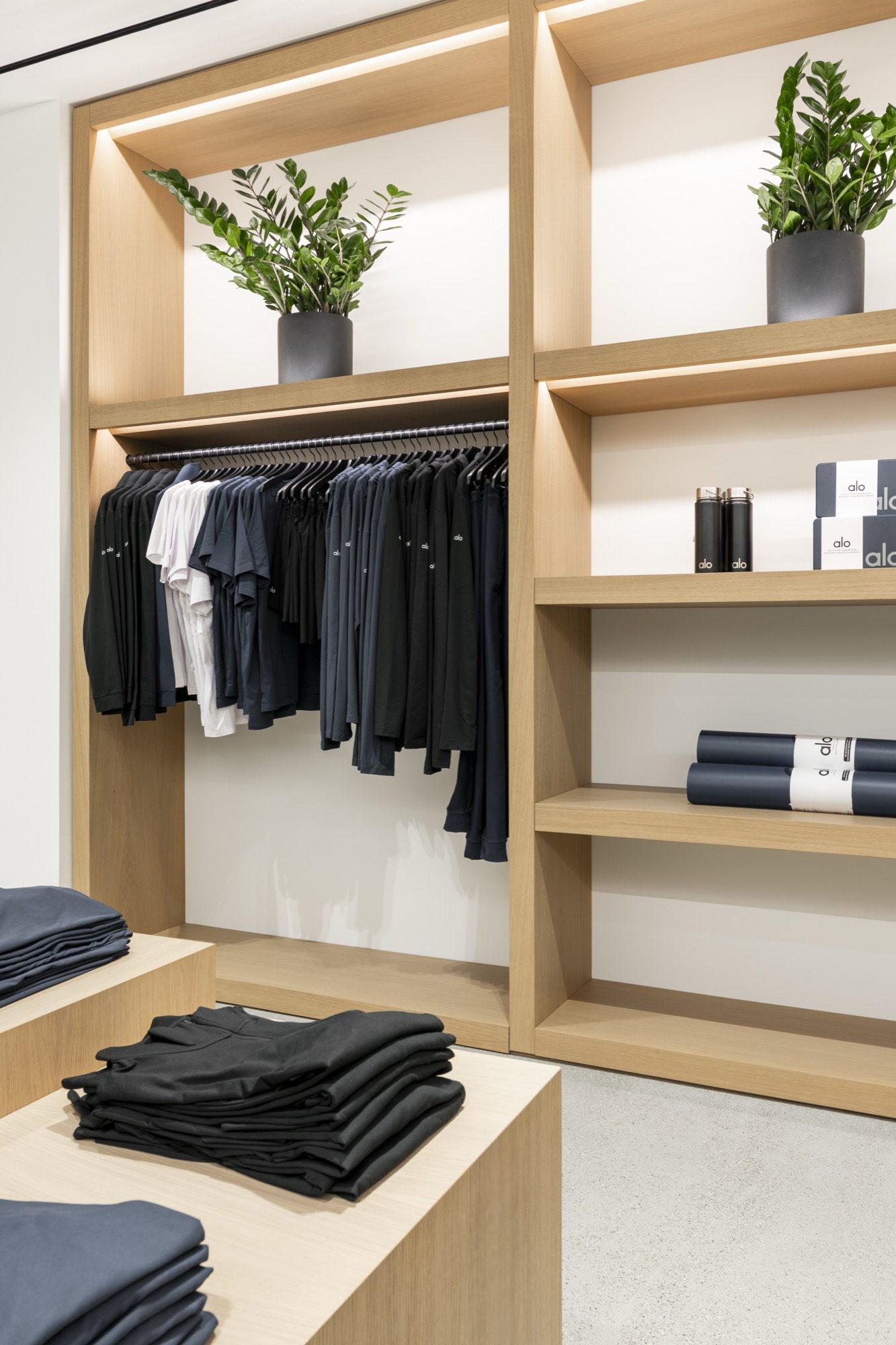 Oak shelving and hanging rails with folded apparel, water bottles and yoga mats