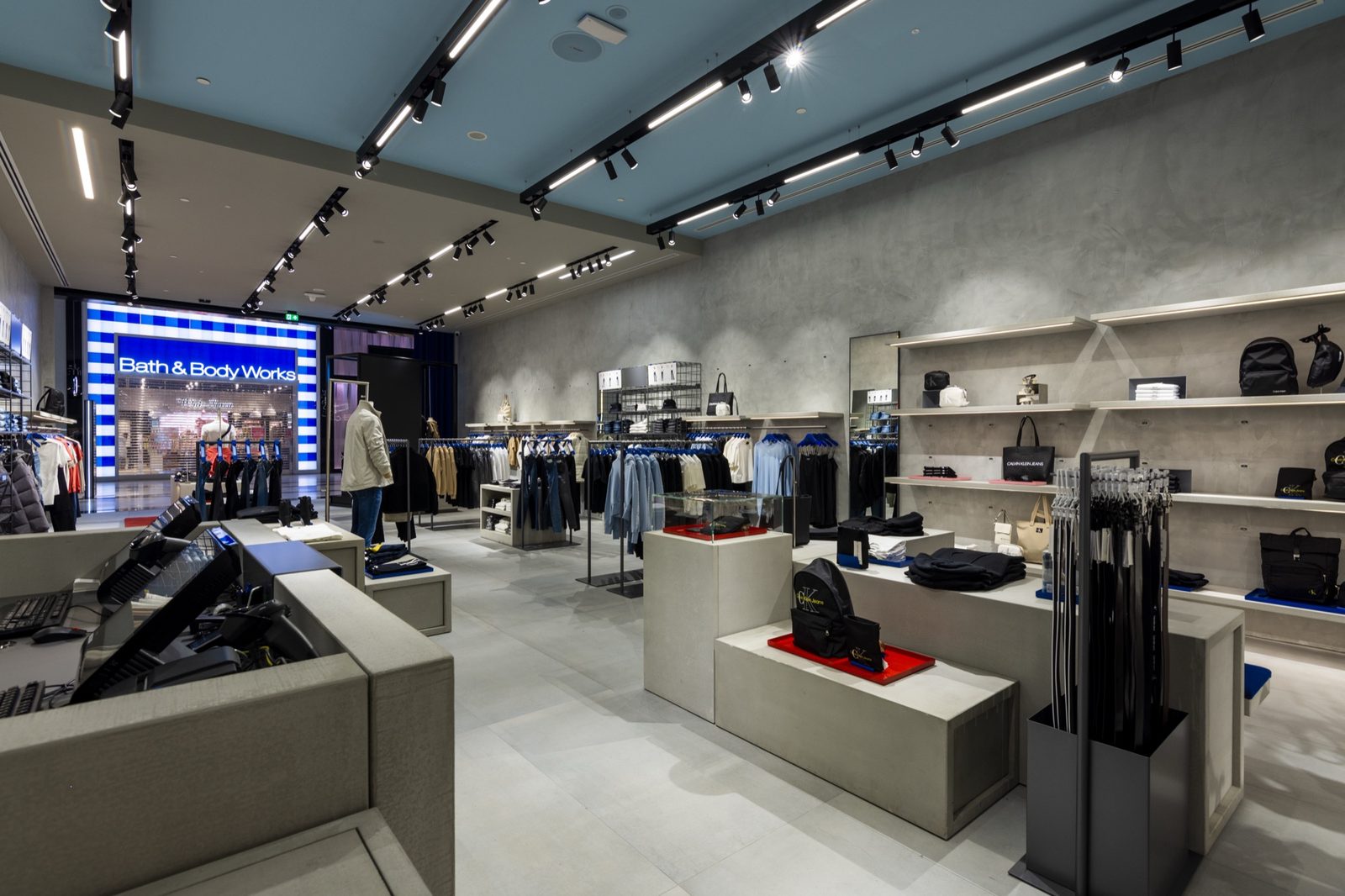 Store interior with polished concrete walls, track lighting, a blue-painted ceiling bay and cast-concrete display plinths
