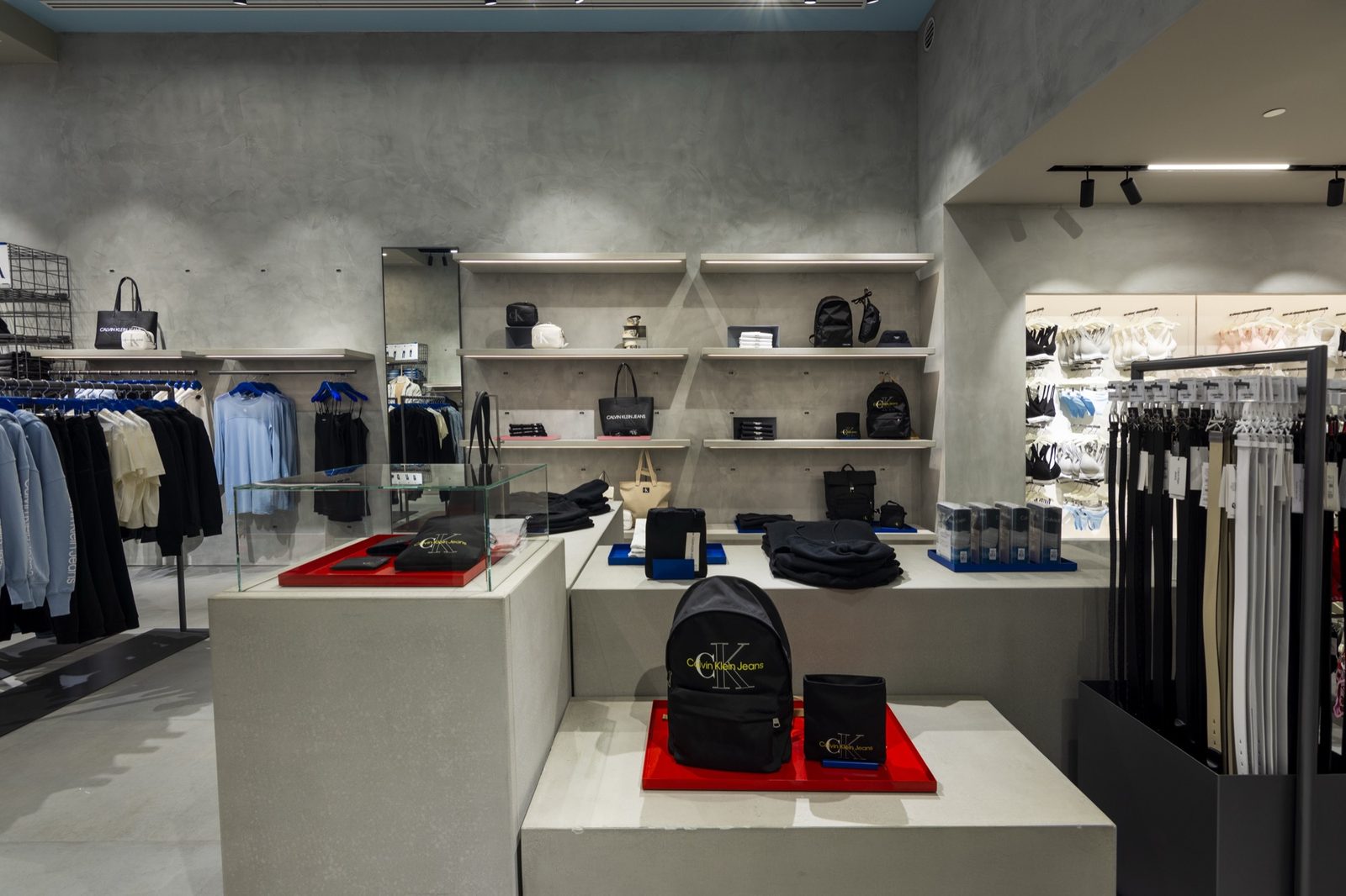 Wall shelving in polished concrete with bags and accessories, beside a full-height mirror