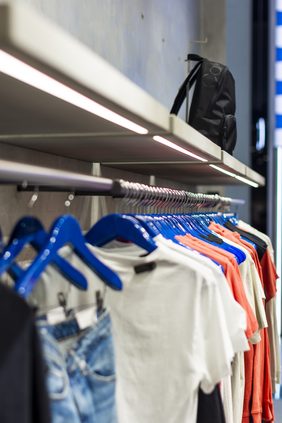 Wall-mounted shelves with crossbody bags against a polished concrete wall