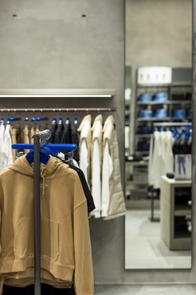 Illuminated shelf above a hanging rail of shirts on blue and red hangers