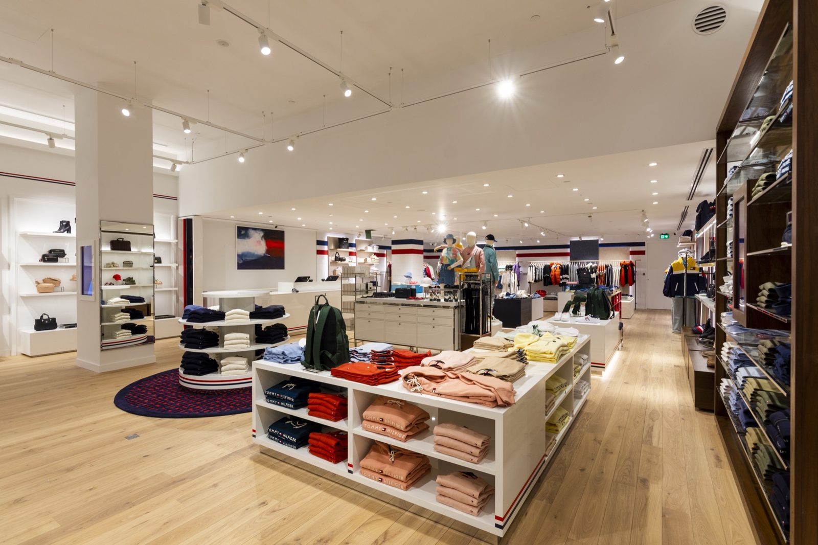 Store floor with white display units, a light oak floor, track lighting and red, white and blue banding