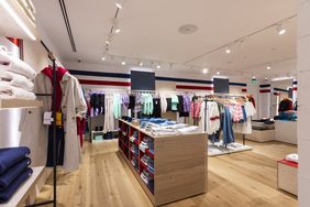Store interior with central display tables and wall rails under track lighting