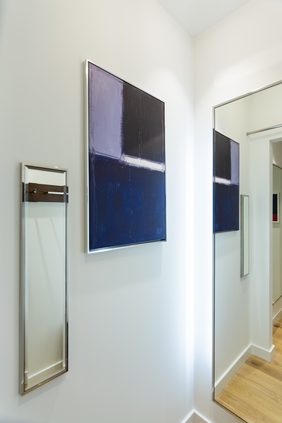 Fitting room corridor with a framed blue painting between two full-height mirrors