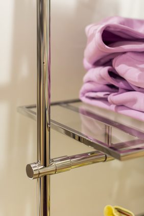 Detail of a chrome display stand with folded garments on a glass shelf