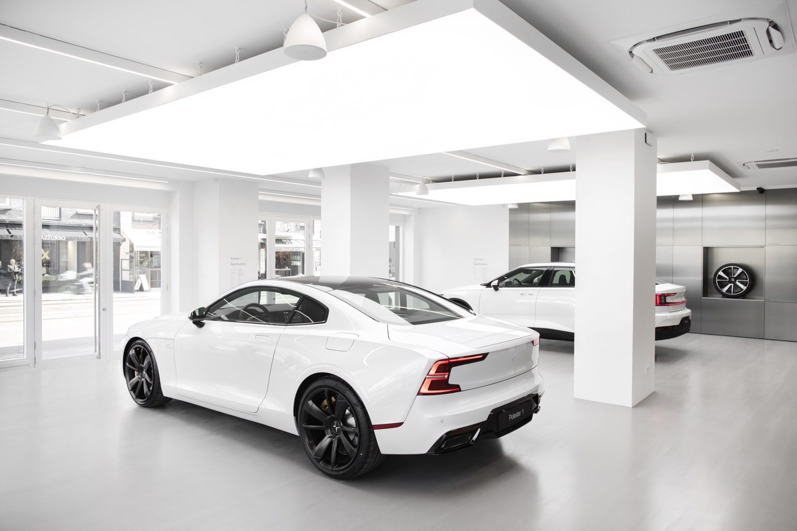 Showroom interior with a white sports car beneath a suspended luminous ceiling panel