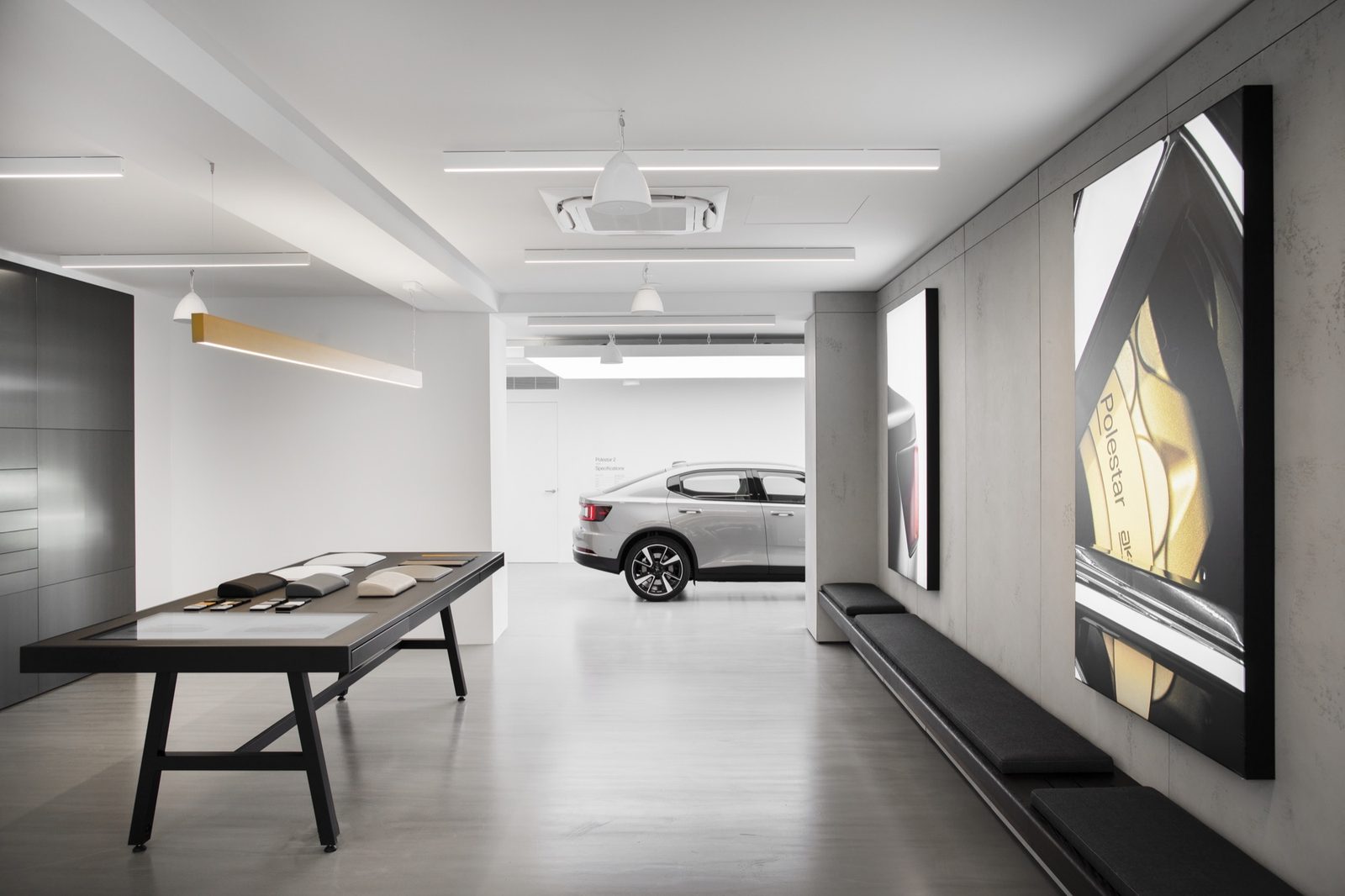 Showroom corridor with a materials sample table, concrete-look wall panels and backlit brand panels