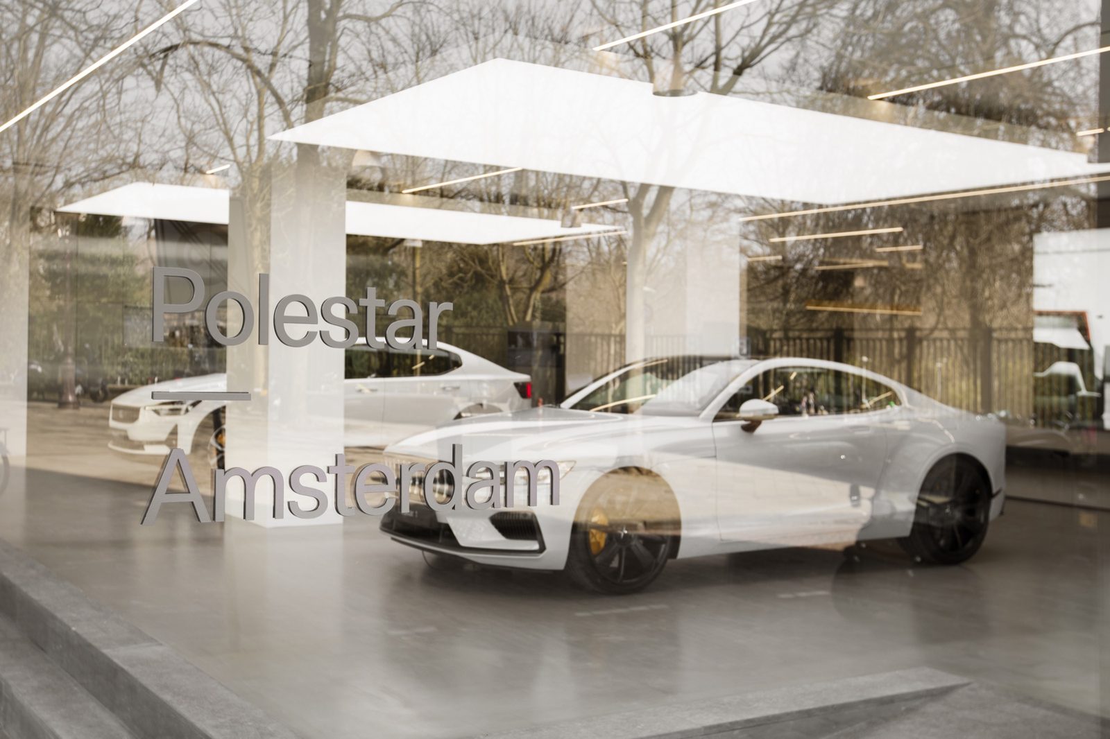 Brand lettering applied to the glazed shopfront, with cars visible inside
