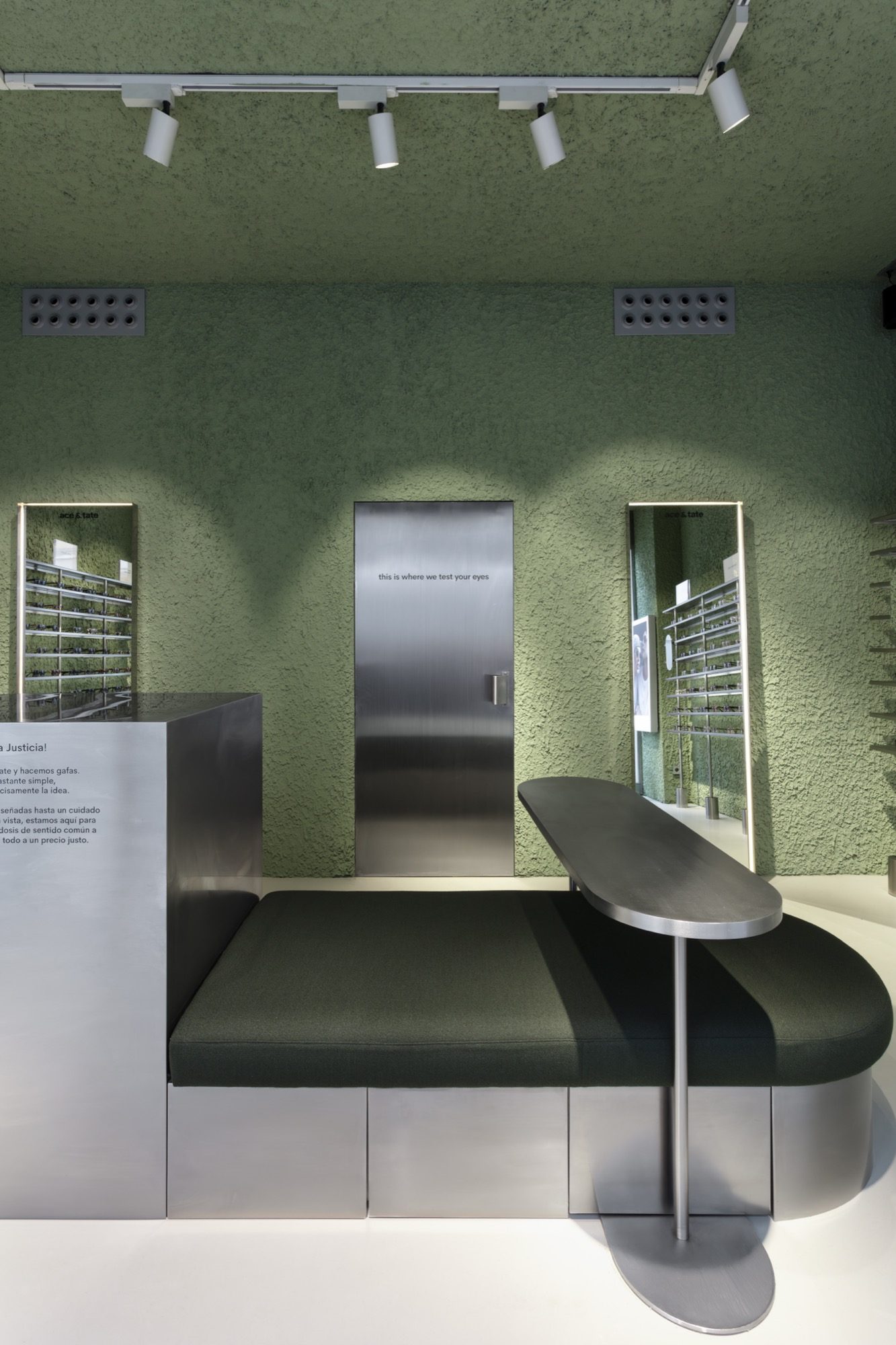 Optician's examination room with a phoropter, imaging unit and examination chair against green textured plaster