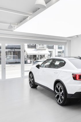 Showroom with a white car beside the fully glazed shopfront, an illuminated stretch ceiling panel and a seamless poured floor